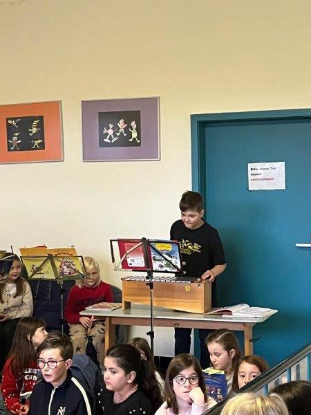  Ein Kind spielt Xylophon, mehrere Kinder sitzen im Vordergrund