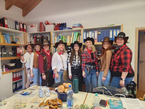 Frauen in Cowboy-Fasnachtsverkleidung stehen nebeneinander und lächeln in die Kamera