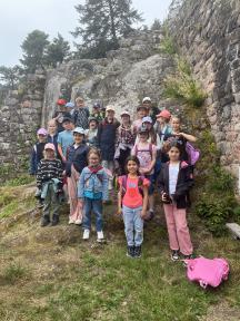 Eine große Gruppe von Kindern und Jugendlichen posiert vor einer massiven Felswand an einem natürlichen Aussichtspunkt.