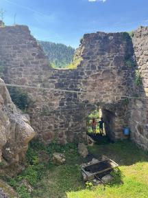 Die massiven Steinruinen einer alten Burg oder Festung vor einer grünen Landschaft.