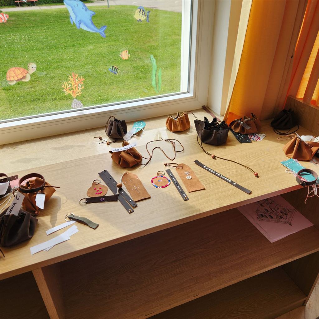 Fensterbank mit zahlreichen kleinen Taschen und Accessoires vor Blick auf eine grüne Rasenfläche.