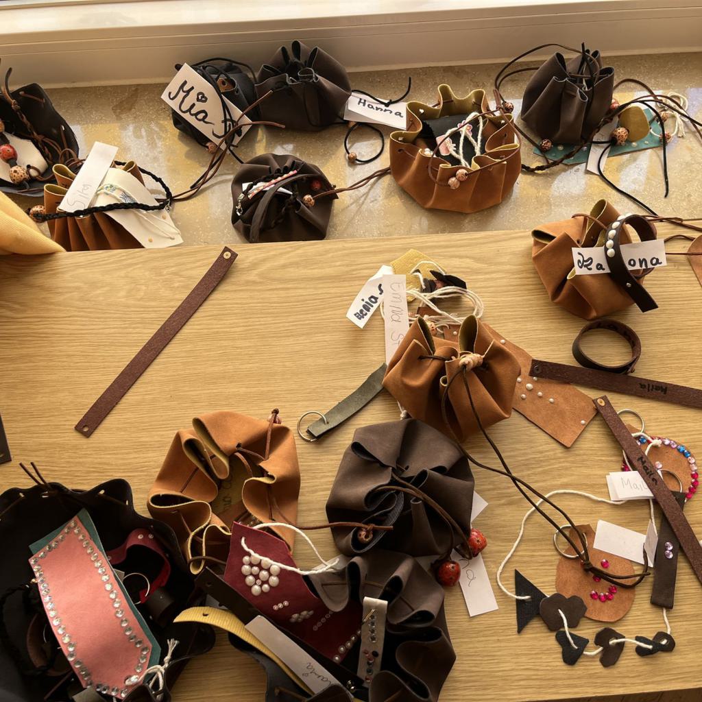 Eine große Auswahl verschiedener Damenhandtaschen und Accessoires, die auf einem Tisch ausgebreitet sind.
