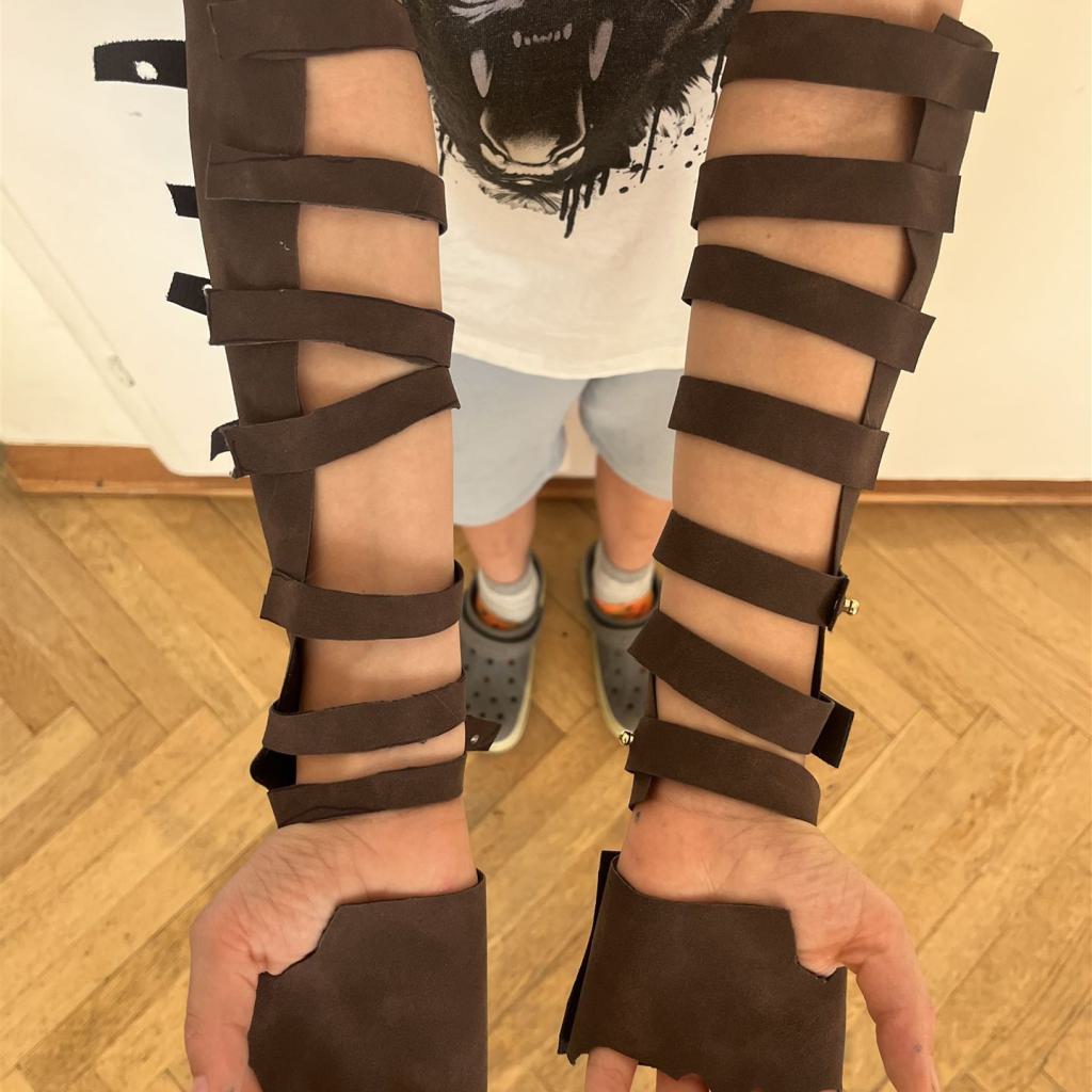 Unterarme und Hände werden mit dunklen Bandagen oder Schienen gestützt.