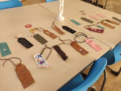 Eine Sammlung verschiedener, handgemachter Anhänger aus Leder und Stoff, die auf einem Tisch ausgebreitet sind.