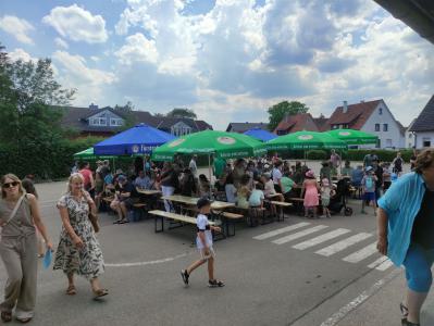 Eine Gruppe von Menschen hält sich auf einem großen Platz bei einer Outdoor-Veranstaltung auf.