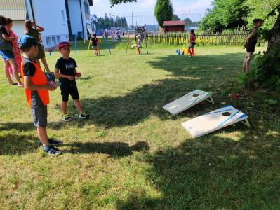 Kinder spielen im Freien auf einer großen Rasenfläche mit Sportbrettern im Vordergrund.